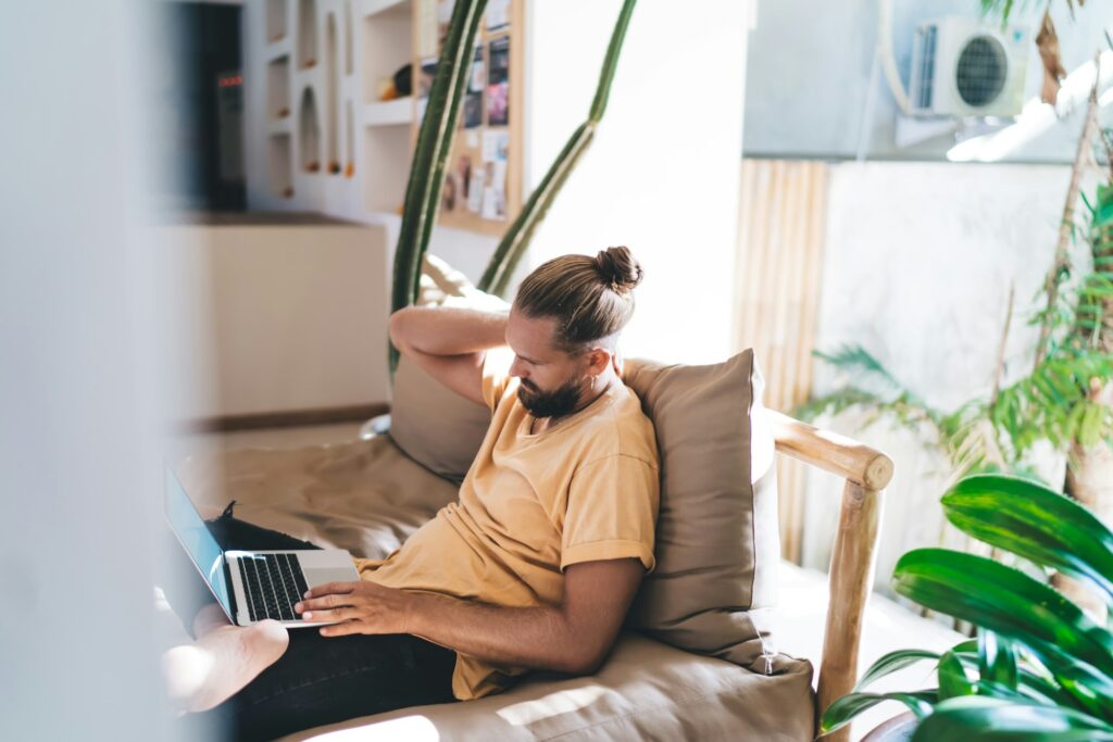 Male blogger searching video content in social media using laptop computer on freelance,
